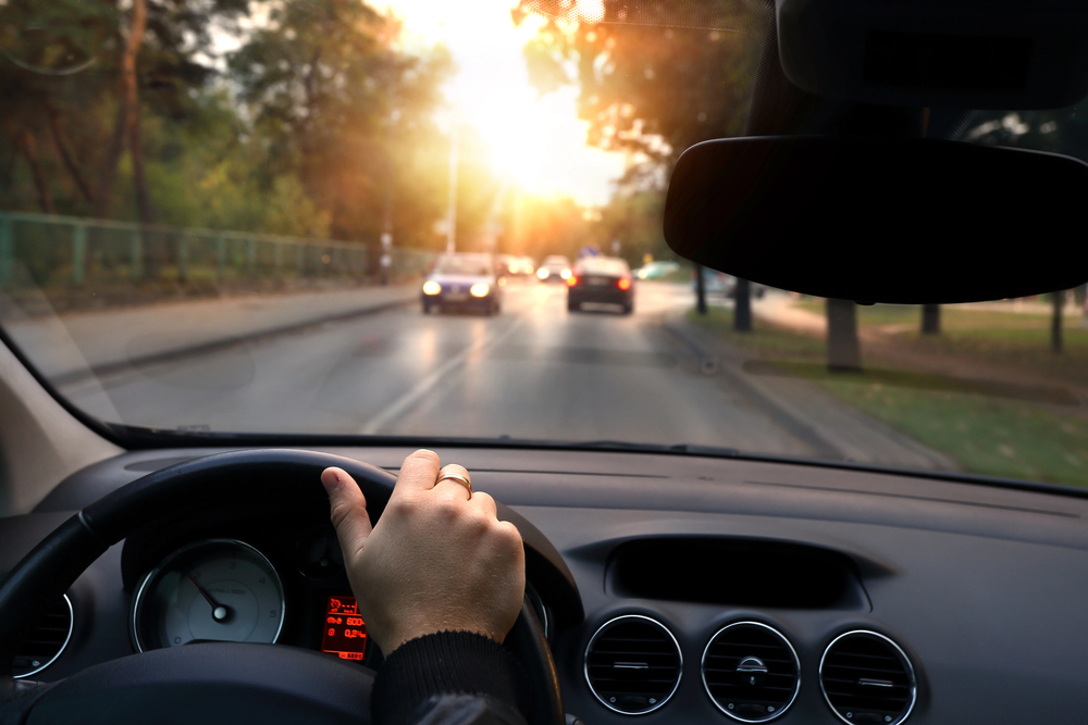 Aufnahme aus der Innenperspektive eines Autos mit Blick auf das Lenkrad und die Straße