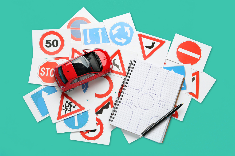 Bild mit auf Papier gedruckten Verkehrszeichen, einem beschriebenem Block und einem Spielzeugauto